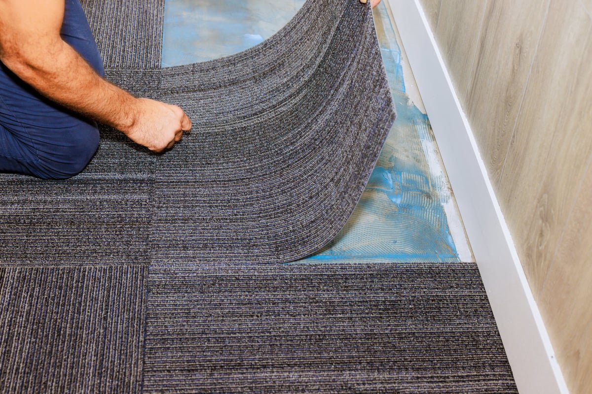 Worker installing gray carpet tiles