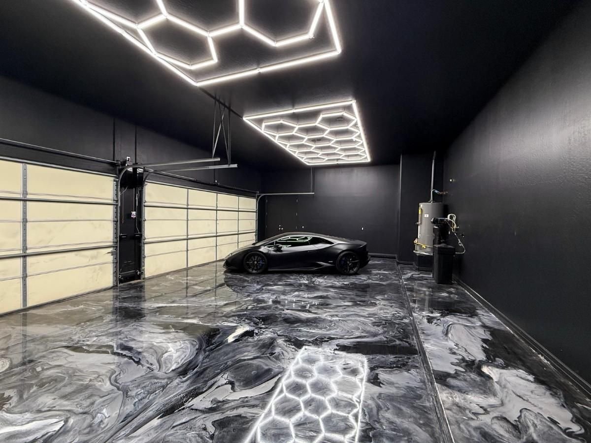 Modern minimalist garage with black sports car, hexagonal neon ceiling lights, marble flooring, and frosted glass garage door